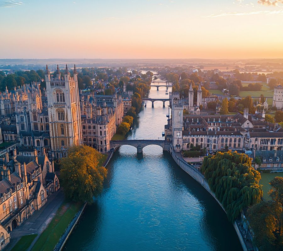 Aerial view of Cambridge at sunrise, showing the River Cam, bridges, and historic buildings.